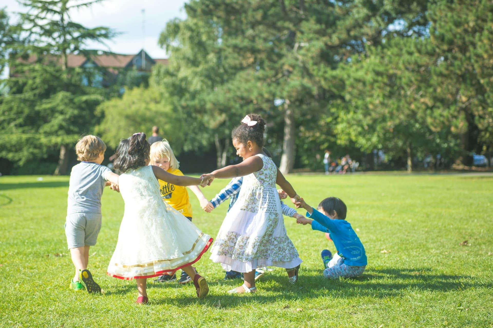 Children holding hands and playing in a circle on the grass